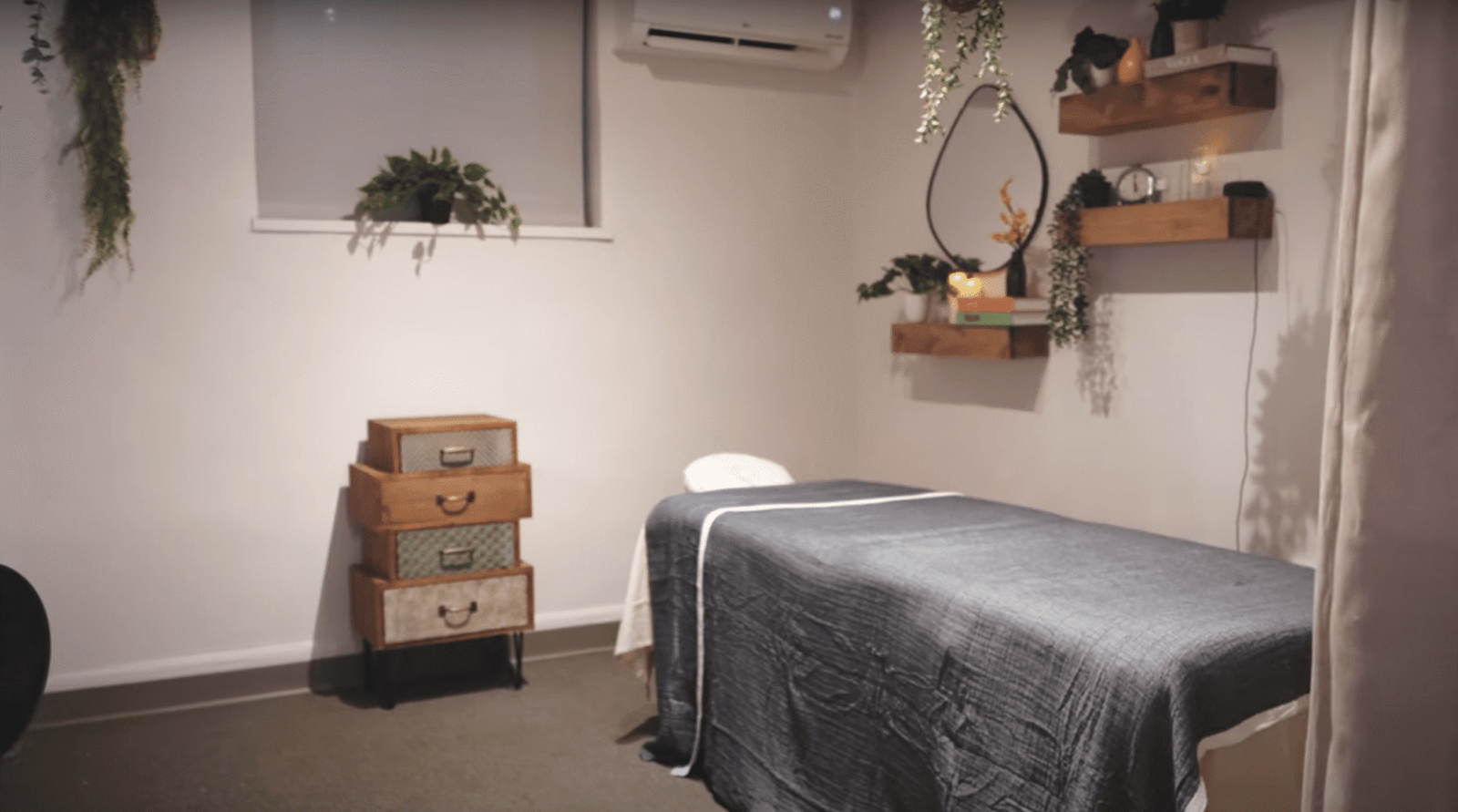 Calm massage treatment room in NYC with plants, candles, and soft lighting for therapists or estheticians. Salon Suite Rental