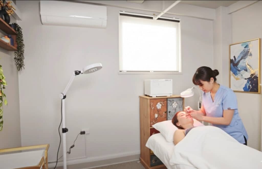 Acupuncturist performing facial acupuncture in a modern treatment room for rent in NYC.