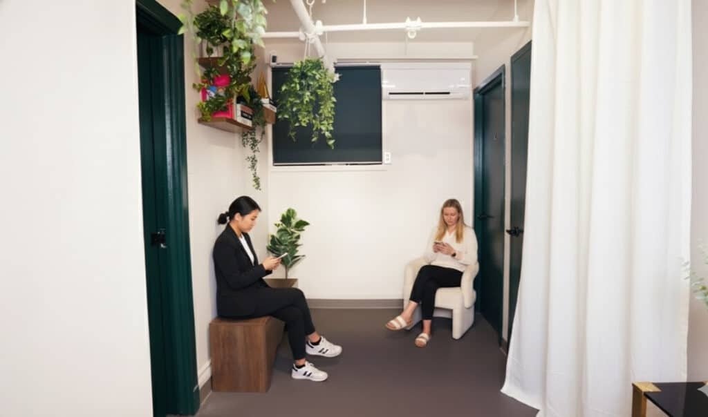Modern waiting area inside beauty suite for rent Manhattan with two women seated, surrounded by greenery.
